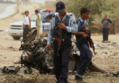 
Iraqi police inspect the wreckage of a suicide car bomb that killed three fellow officers Wednesday in Baghdad. 
 (Associated Press / The Spokesman-Review)
