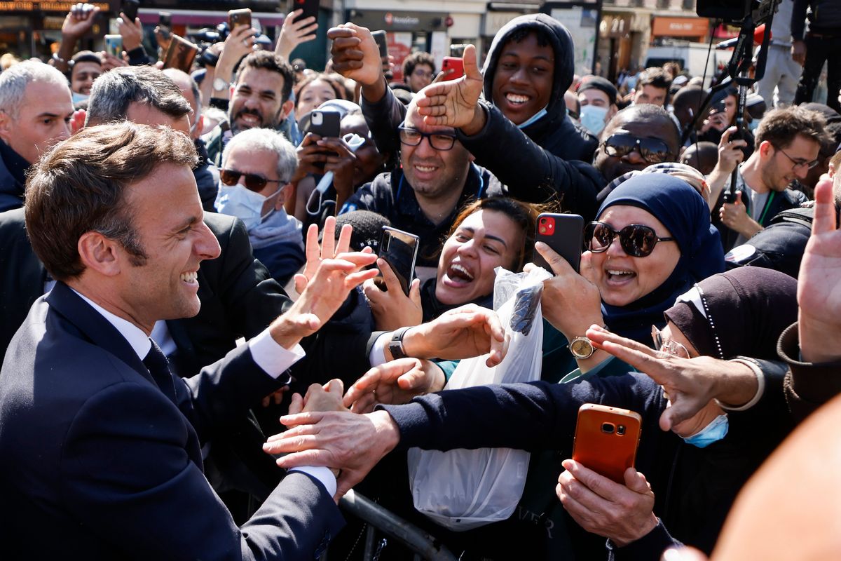 Centrist presidential candidate and French President Emmanuel Macron holds hands to residents during a campaign stop Thursday, April 21, 2022 in Saint-Denis, outside Paris. French voters head to polls on Sunday in a runoff vote between centrist incumbent Emmanuel Macron and nationalist rival Marine Le Pen. (Ludovic Marin)