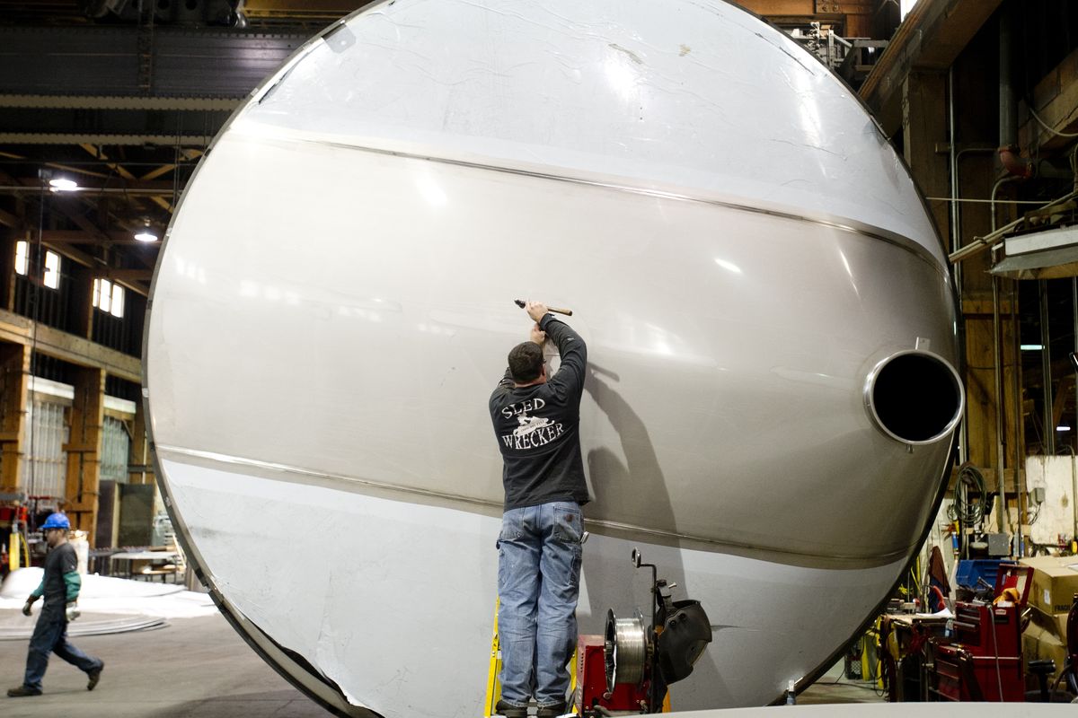 Welder Curt Hayes uses a hammer to make adjustments to a giant wine vessel on Tuesday at Spokane Industries.