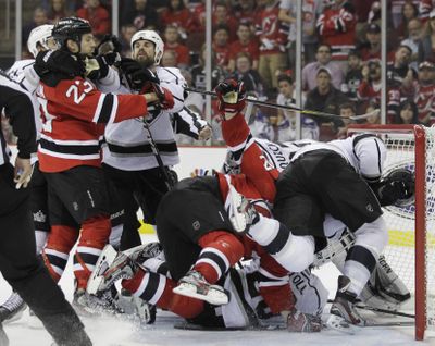 New Jersey Devils and Los Angeles Kings players grapple near the goal in the third period during Game 5. (Associated Press)