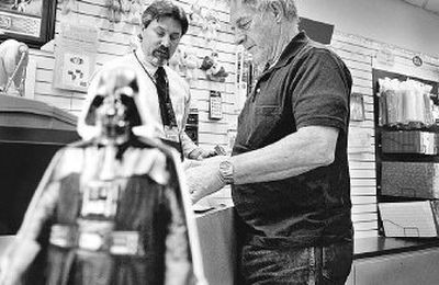 
With Darth Vader nearby, Rosewood postal branch manager Steven Pagel, left,  helps  Dennis Christman with  