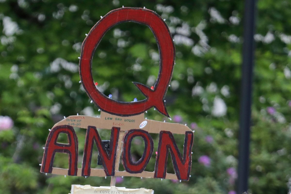FILE - A person carries a sign supporting QAnon during a protest rally in Olympia, Wash., on May 14, 2020. The QAnon conspiracy theory has been linked to acts of real-world violence, including last year
