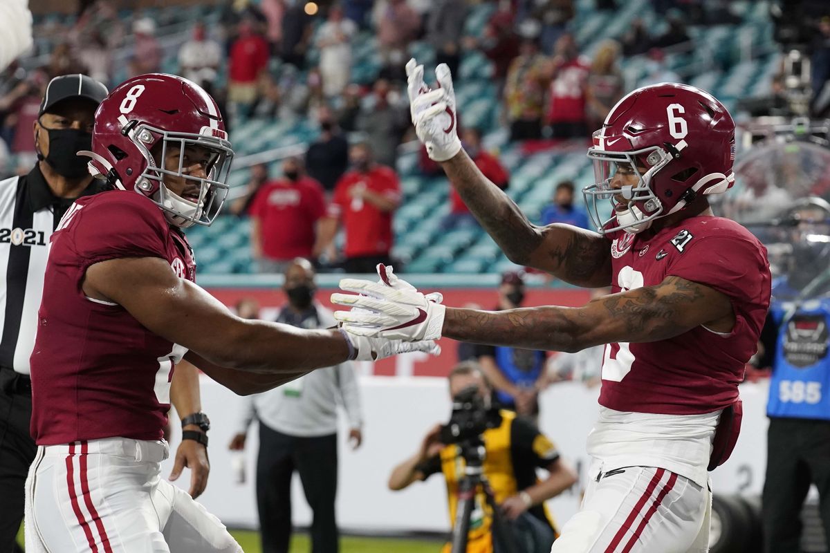 Alabama wide receiver John Metchie III, left, congratulates wide receiver DeVonta Smith, after Smith scored a touchdown against Ohio State during the first half of an NCAA College Football Playoff national championship game, Monday, Jan. 11, 2021, in Miami Gardens, Fla.  (Chris O