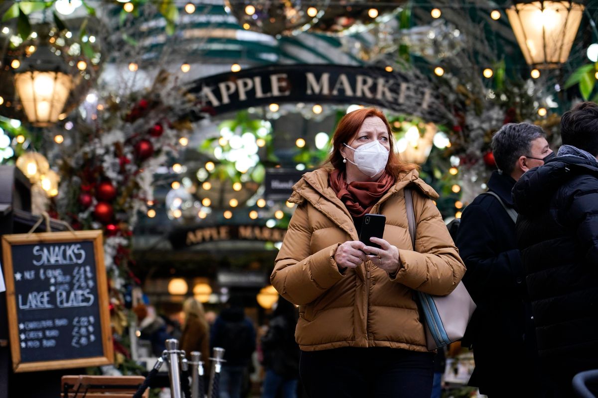 A woman wears a face mask as she walks in Covent Garden market, in London, Thursday, Dec. 16, 2021. The U.K. recorded the highest number of confirmed new COVID-19 infections Wednesday since the pandemic began, and England