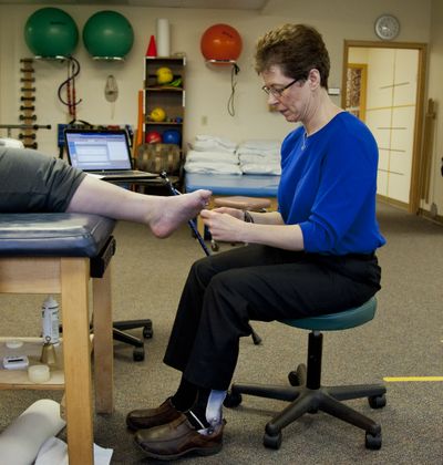 Susan Gray works on a patient’s surgically repaired foot recently at Northside Physical Therapy in Spokane. Gray, 46, had a stroke nine years ago and uses a cane and leg brace. (Dan Pelle)