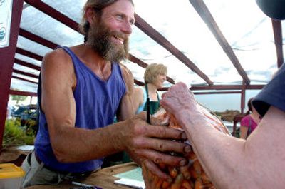 
Farmer Paul Smith sells a bag of fresh carrots Wednesday afternoon at the midweek Kootenai County Farmers Market at Prairie Avenue and U.S. 95. He will donate a large amount of produce to the upcoming Feast with the Farmers dinner. 
 (Jesse Tinsley / The Spokesman-Review)