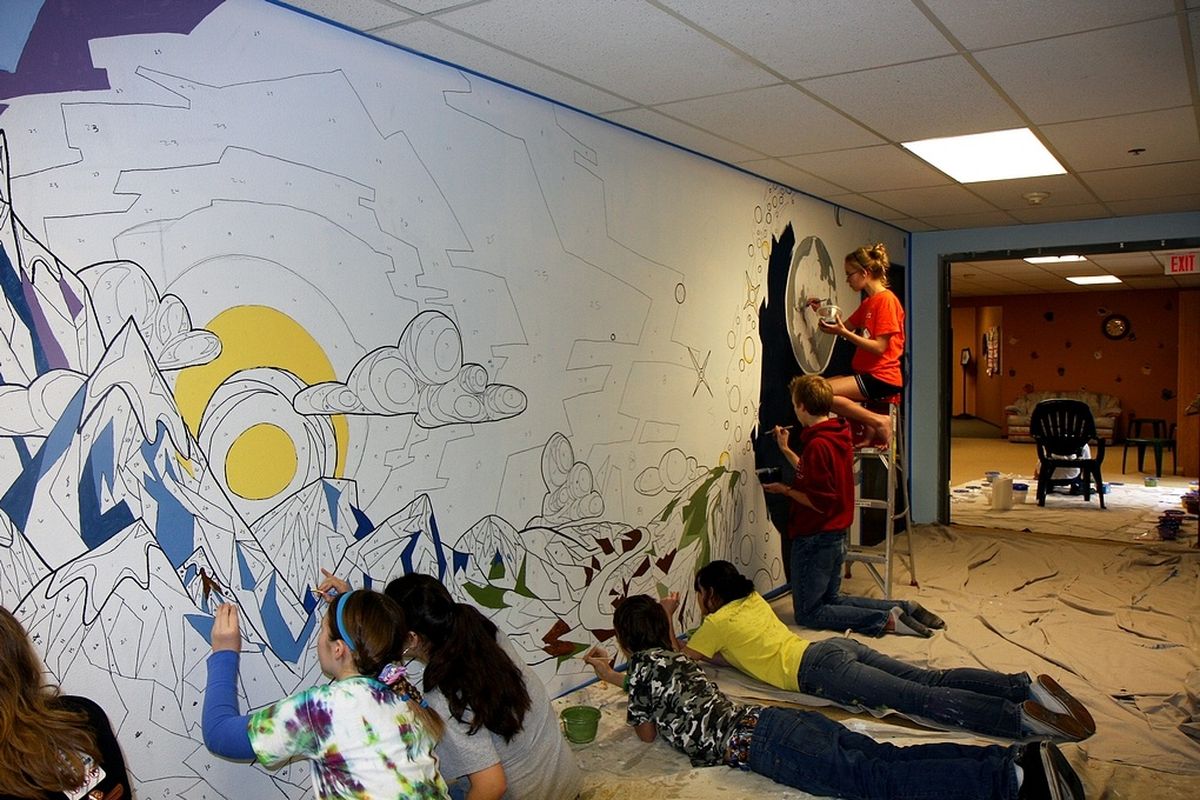 Volunteers help paint a mural designed by Scott Coffey.