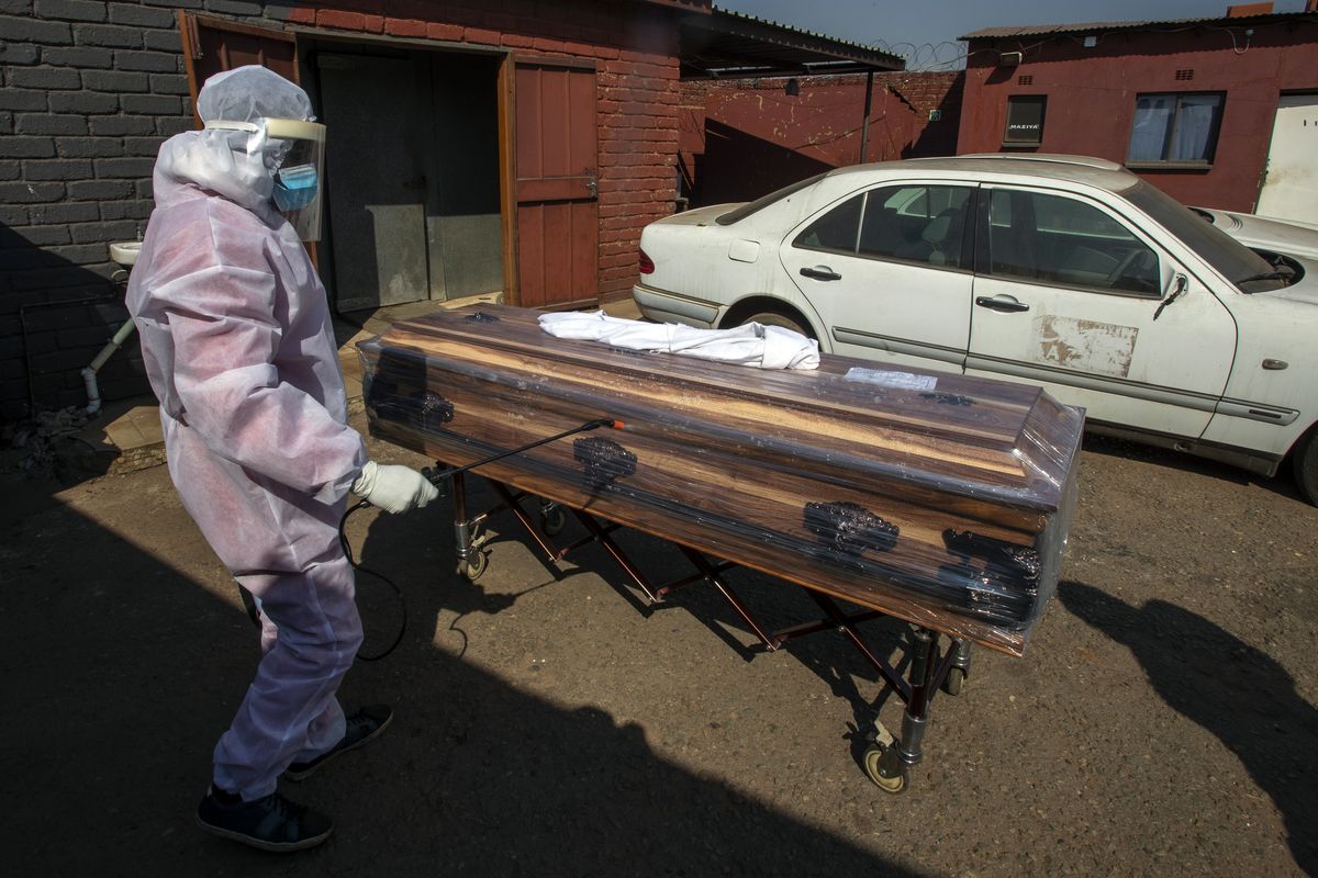 A funeral home worker in A protective suit disinfects a coffin carrying a woman who died from COVID-19, as they prepare for a funeral in Katlehong, near Johannesburg, South Africa, Tuesday, July 21, 2020. South Africa, last Saturday became one of the top five worst-hit countries in the coronavirus pandemic, as breathtaking new infection numbers around the world were a reminder that a return to normal life is still far from sight.  (Themba Hadebe)