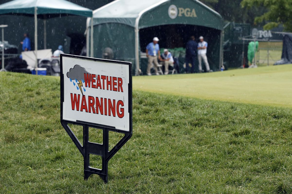 Workers wait under a tent at the practice green after third-round play was suspended Saturday at the PGA Championship. (Tony Gutierrez / Associated Press)