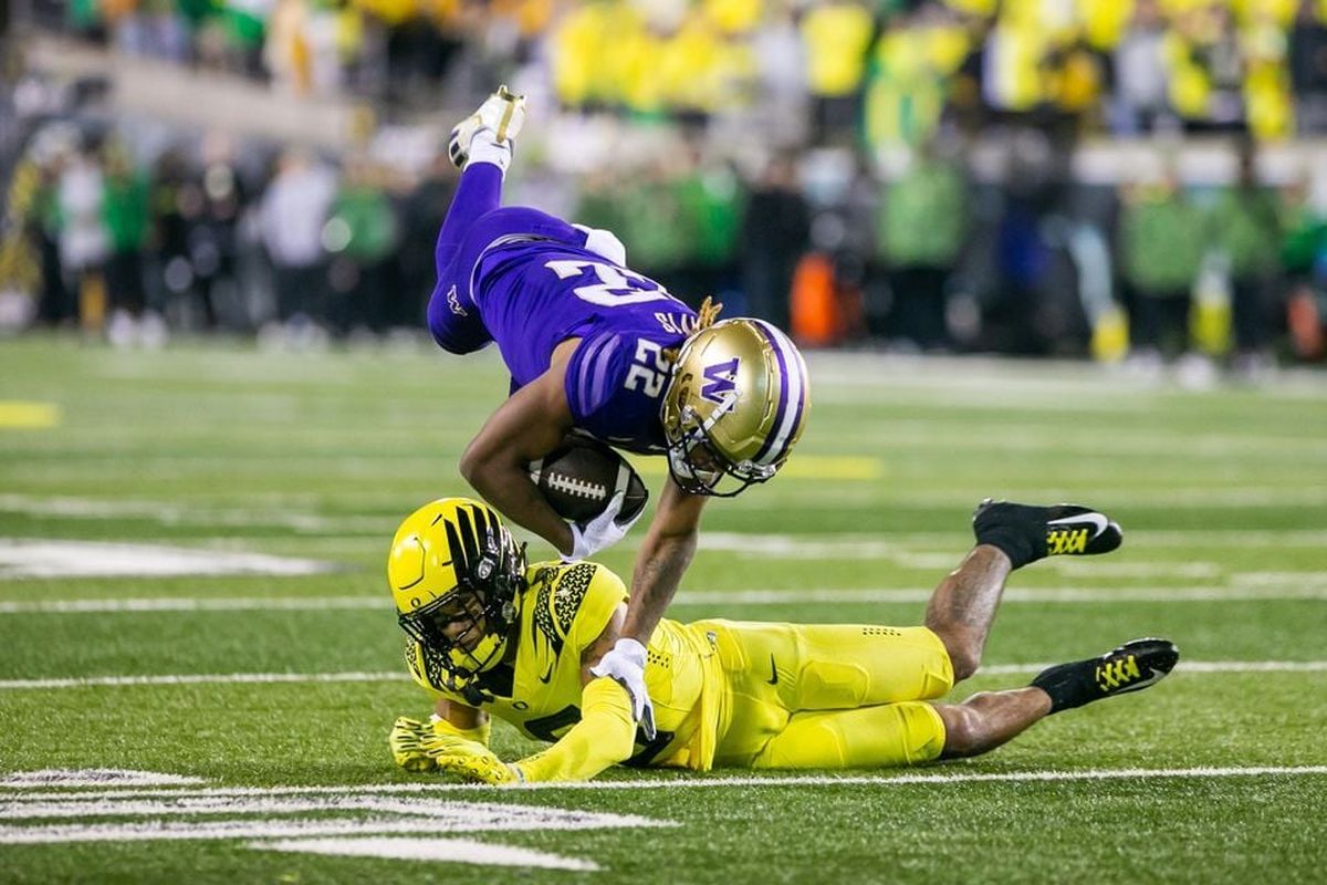 Oregon cornerback Christian Gonzales upends Washington running back Cameron Davis in the 2022 game between the two at Autzen stadium in Eugene.  (Sean Meagher)