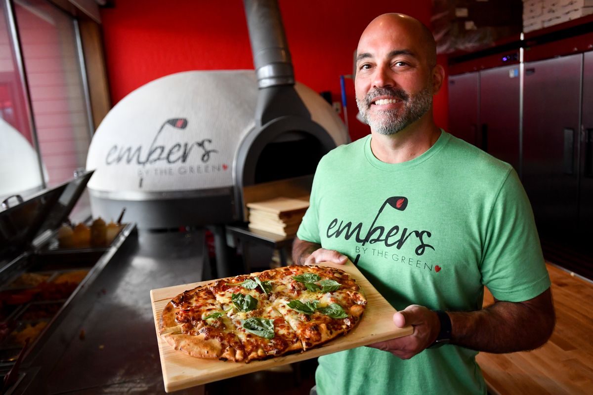 Rob Burnett, owner of Embers by the Green, stands with a Papa Guido pie in front of Ember’s pizza oven Thursday at Embers by the Green in Post Falls.  (Tyler Tjomsland/The Spokesman-Review)