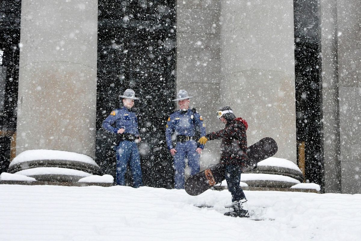 State troopers tell Ryan Carter, a Rochester, Wash., construction worker, he has to stop snowboarding down the north steps of the Legislative Building in Olympia during the heavy snowstorm Monday in Western Washington. (Jim Camden / The Spokesman-Review)