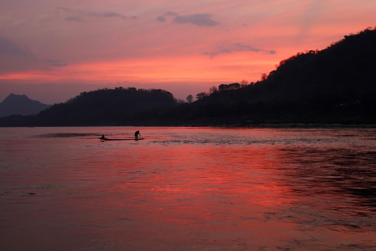 In this March 4, 2011, file photo, men ride in a boat across the Mekong River in Luang Prabang, Laos. It is officially described as the best-preserved city in Southeast Asia, a bygone seat of kings tucked into a remote river valley of Laos. Luang Prabang weaves a never-never land spell on many a visitor with its tapestry of French colonial villas and Buddhist temples draped in a languid atmosphere. (Jacquelyn Martin / AP)