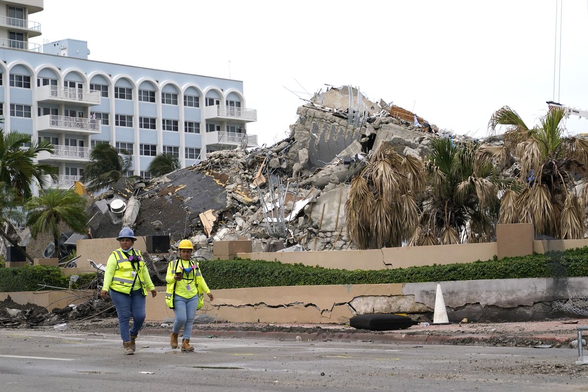 Workers walk past the collapsed and subsequently demolished Champlain Towers South condominium building, Tuesday, July 6, 2021, in Surfside, Fla.  (Lynne Sladky)