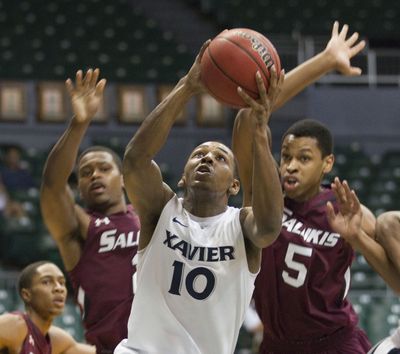 Xavier guard Mark Lyons (10) splits Southern Illinois guard Kendal Brown-Surles, left, and forward Antonio Bryer (5) on the way to the basket in the first half of an NCAA college basketball game on Christmas Day in Honolulu. (Associated Press)