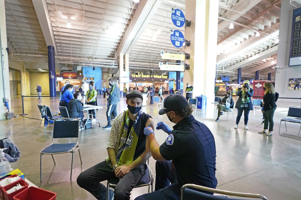 Austin Kennedy, left, a Seattle Sounders season ticket holder, gets the Johnson & Johnson COVID-19 vaccine at a concourse clinic May 2 at Lumen Field prior to an MLS match between the Sounders and the Los Angeles Galaxy.  (Ted S. Warren)