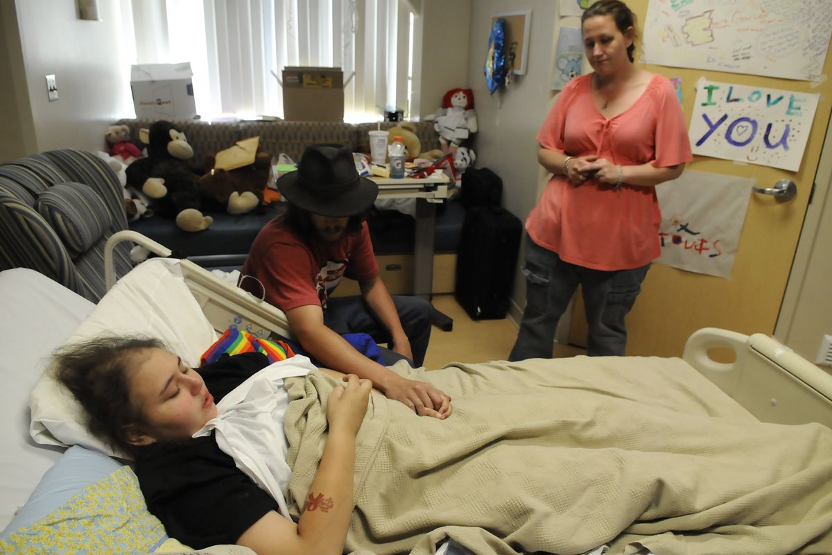Alicia Ponce-Myers, 12, is comforted by her parents, Daniel and Brooke Angell. Alicia has been at Providence Sacred Heart Children’s Hospital receiving treatments for childhood acute lymphoblastic leukemia, which is now in remission. (Dan Pelle)