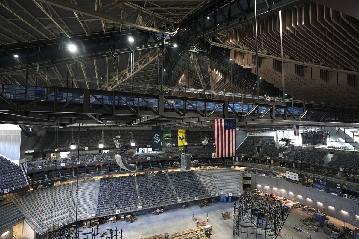 The interior beams of the historic peaked roof of the Climate Pledge Arena rise above the United States and team flags during a media tour of the facility, Monday, July 12, 2021, in Seattle. The arena will be the home of the NHL hockey team Seattle Kraken and the WNBA Seattle Storm basketball team as well as hosting concerts and other performing arts events.  (Ted S. Warren)