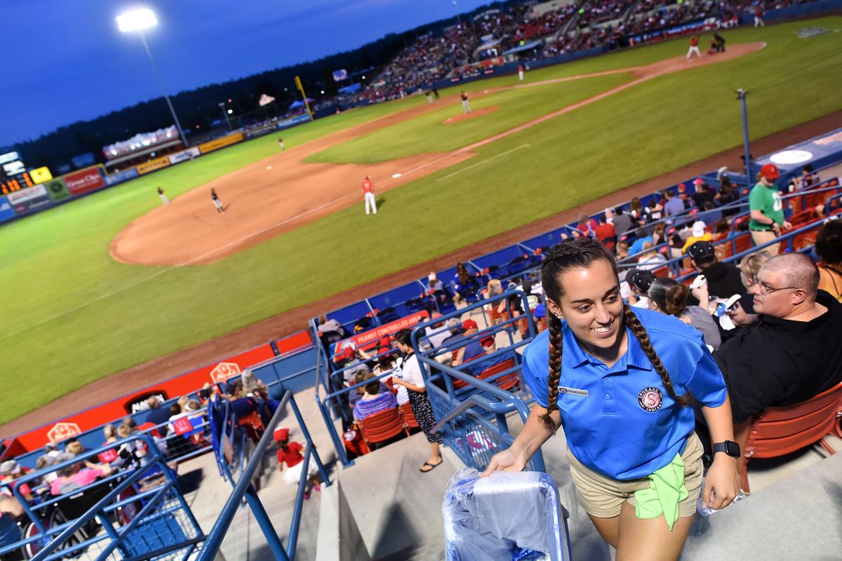 Spokane Indians section leader Doriann Atiqi, 18, smiles as she collects cans and bottles from fans to be recycled as the Indians face the Vancouver Canadians on Friday, Aug. 16, 2019, at Avista Stadium in Spokane, Wash. (Tyler Tjomsland / The Spokesman-Review)