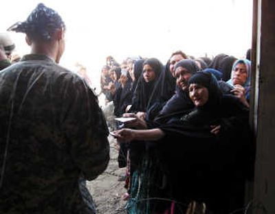 
Iraqi women line up for food as U.S. soldiers check their documents Monday in Baqouba. Since the beginning of combat operations last month, residents have not been able to go  for groceries. Associated Press
 (Associated Press / The Spokesman-Review)