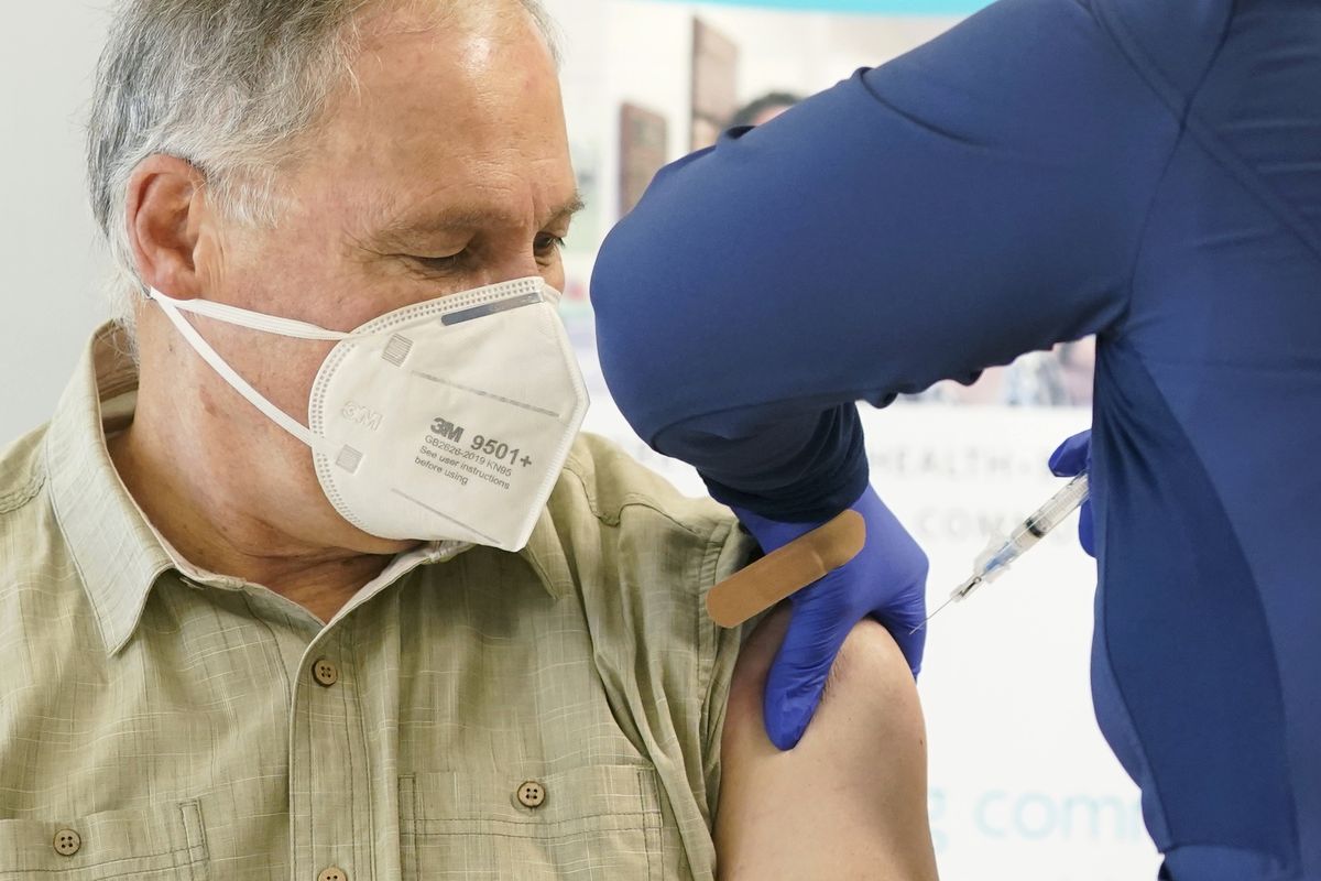 Washington Gov. Jay Inslee, left, gets the first shot of the Moderna COVID-19 vaccine, Friday, Jan. 22, 2021, from Elizabeth Smalley, right, a medical assistant at a Sea Mar Community Health Center in Olympia, Wash. Inslee