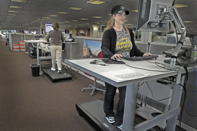 Pitney Bowes service and field-support agent Jenni Lindsey, right, and purchase power agent Sandy Epps work on walking stations at the company call center in Spokane on Tuesday. The upright stations feature a slow-moving treadmill and are in high demand by employees who prefer to stand while working. (Christopher Anderson)