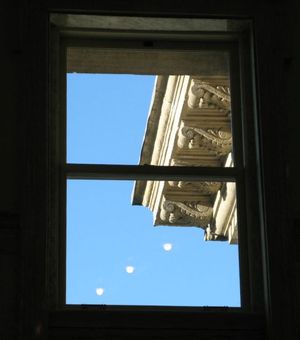 Framed through a third-floor window of the state Capitol, it's a blue-sky morning Thursday; the tiny white decorative lightbulbs inside the rotunda are reflected in the window against the sky. (Betsy Russell)