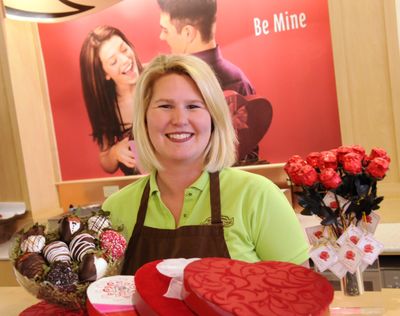 Rachelle Blackmer shows off  a box of chocolate-dipped strawberries, boxes of chocolate and a vase of chocolate roses at  Rocky Mountain Chocolate Factory, 506 N. Sullivan Road. (J. BART RAYNIAK)