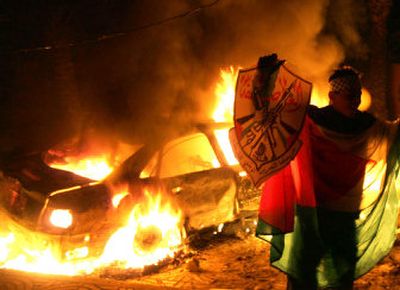 
A protester holds a Fatah badge next to a burning car inside the courtyard of the Parliament in Gaza City on Friday. Thousands of Fatah members burned cars and fired shots in the air in demonstrations across the Gaza Strip. 
 (Associated Press / The Spokesman-Review)