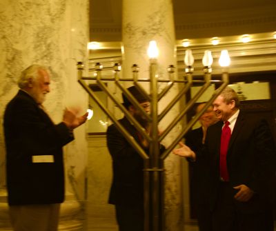 Rep. Hy Kloc, left, Attorney General Lawrence Wasden, right, and Rabbi Mendel Lifschitz, center, after the lighting of a Chanukah menorah in the state Capitol rotunda on Tuesday evening