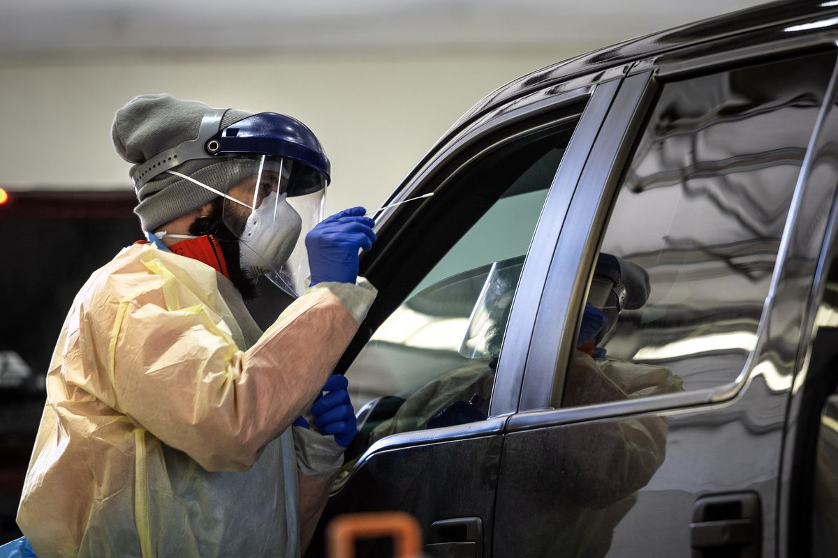 A healthcare worker prepares to do a nasal swab on a person in the newly relocated indoor COVID-19 drive-up screening station at the Spokane Interstate Fair and Expo Center, Thurs., April 2, 2020.   (COLIN MULVANY)
