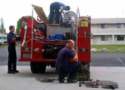
Firefighter Casey Parr, bottom right, checks the brush-fire backpacks while firefighter Scott Crawford, left, and Capt. Kevin Uphus, top, do a routine check of the brush-fire truck at the Millwood Fire Station on Tuesday. Ballots to decide whether to annex the Millwood Fire Department into the Spokane Valley Fire Department were mailed to voters last week. 
 (Liz Kishimoto / The Spokesman-Review)