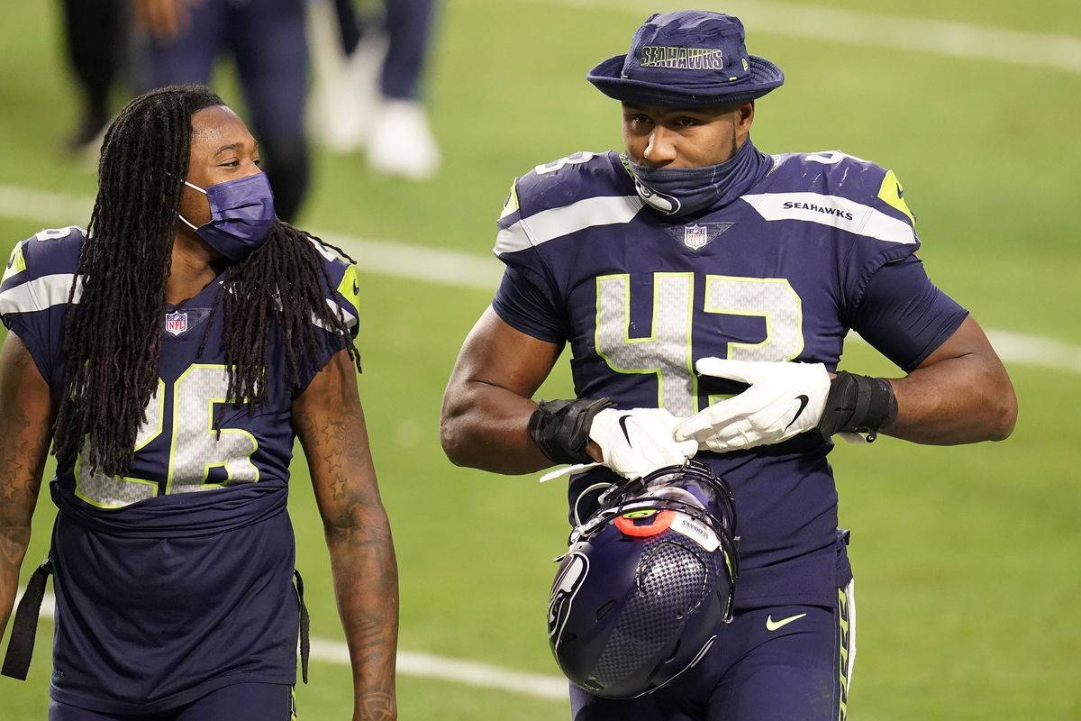 Seattle Seahawks defensive end Carlos Dunlap (43) leave the field with cornerback Shaquill Griffin (26) after an NFL football game against the San Francisco 49ers, Sunday, Jan. 3, 2021, in Glendale, Ariz. The Seahawks won 26-23.  (Ross D. Franklin)
