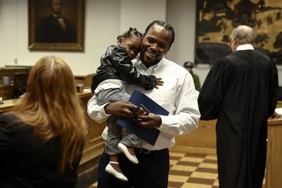 JoJo Fatty, a graduate of the King County Drug Diversion Court program, holds his daughter and smiles as he is recognized during a graduation ceremony on Wednesday in Seattle. (Seattle Times)