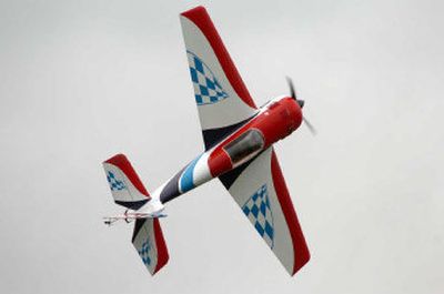 
Jerry Mudge's plane flies on knife edge down the flight line while Mudge was practicing his aerobatic skills. Below, veteran RC flier and former Air Force pilot Neil Udell, right, gives Joshua Heisey, 8, his first flight with a radio-controlled plane using a 