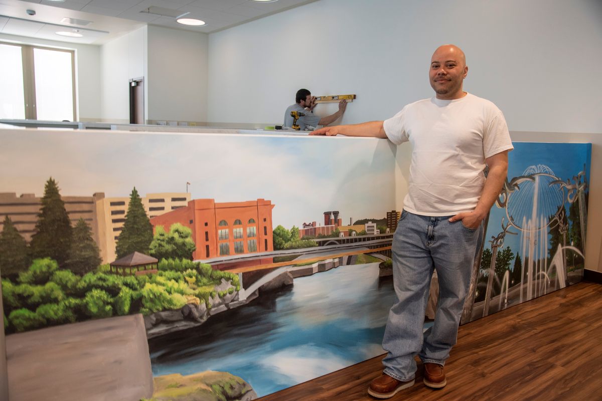 Artist Myron Curry stands with some of his paintings, which were being hung by his friend Johnathan Creach, in back, on Sunday inside the Spokane Regional Stabilization Center.  (Jesse Tinsley/THE SPOKESMAN-REVI)