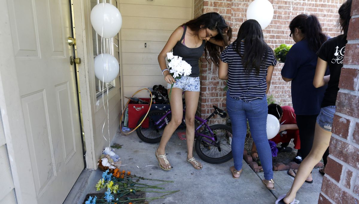 People place flowers and balloons at a house in Houston on Sunday where a family of two parents and six children were killed Saturday. (Associated Press)