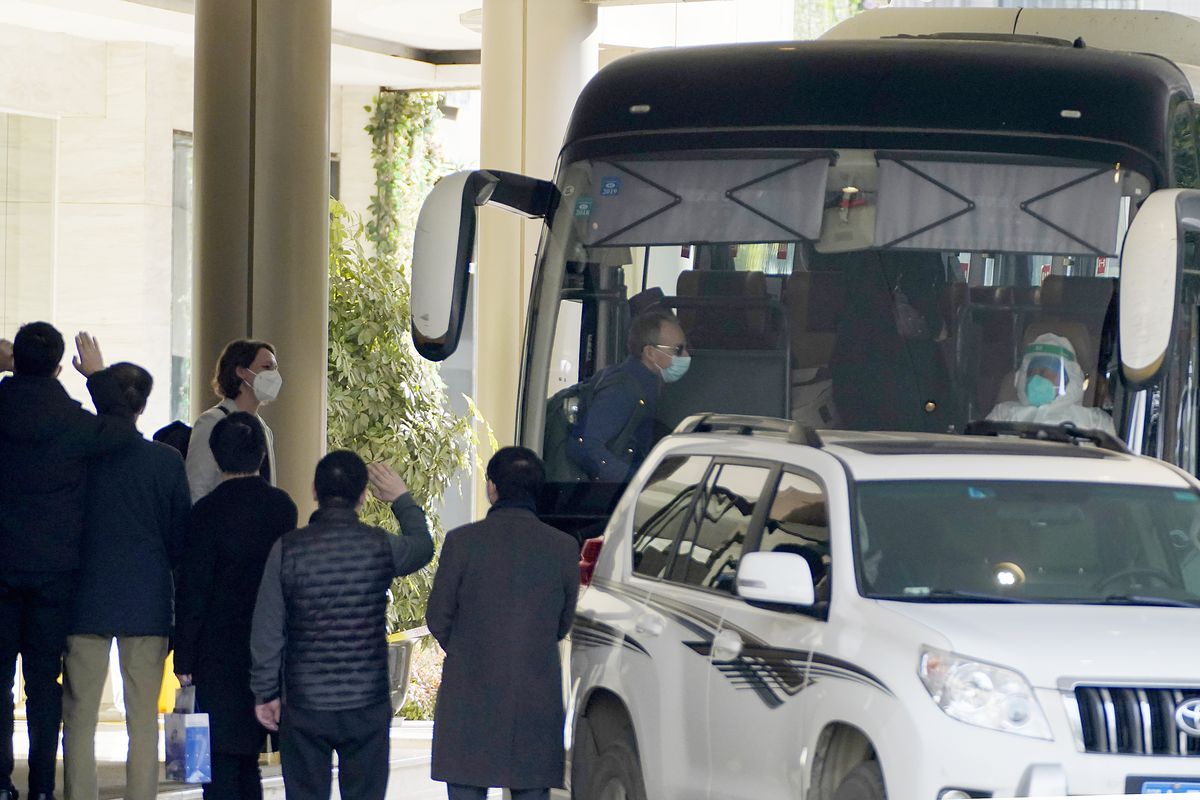 Workers wave to the team of experts from the World Health Organization who ended their quarantine and prepare to leave the quarantine hotel by bus in Wuhan in central China