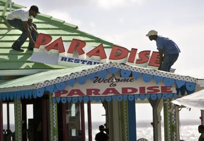 Workers remove a roof sign from Paradise Restaurant on Thursday in preparation for the arrival of the Gustav storm system in George Town on Grand Cayman Island.  (Associated Press / The Spokesman-Review)