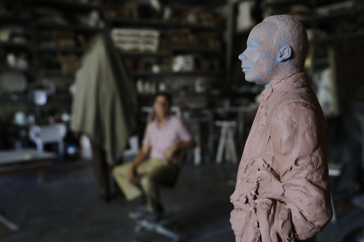 In this Thursday, Aug. 24, 2017, photo, a model of a statue artist Martin Dawe, rear, sculpted paying tribute to civil rights leader Martin Luther King Jr., stands at right as the finished statue is covered at rear left, at Dawe’s studio in Atlanta. (David Goldman / Associated Press)