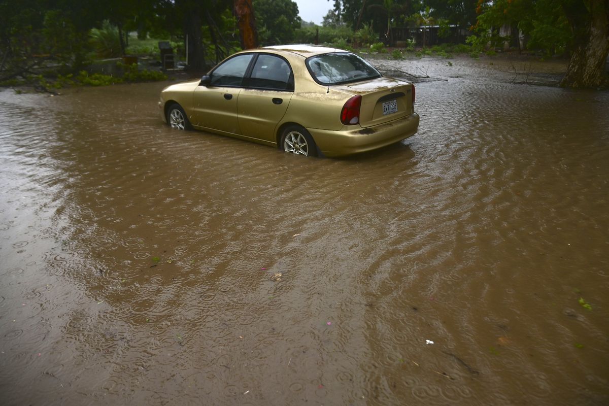 A car sits in flood waters caused by Tropical Storm Laura in Salinas, Puerto Rico, Saturday, Aug. 22, 2020. Laura began flinging rain across Puerto Rico and the Virgin Islands on Saturday morning and was expected to drench the Dominican Republic, Haiti and parts of Cuba during the day on its westward course.  (Carlos Giusti)