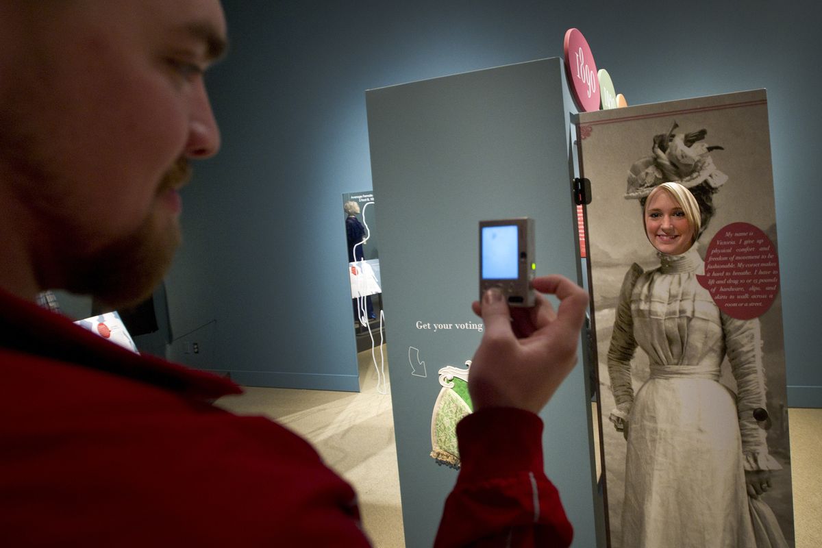 Jake Saxon takes a fun photo of Jennifer Trent modeling a Victorian-era dress at a historical clothing exhibit at the Museum of Arts and Culture on Thursday. Supporters of the MAC also point to its educational and archival missions. (Colin Mulvaney)