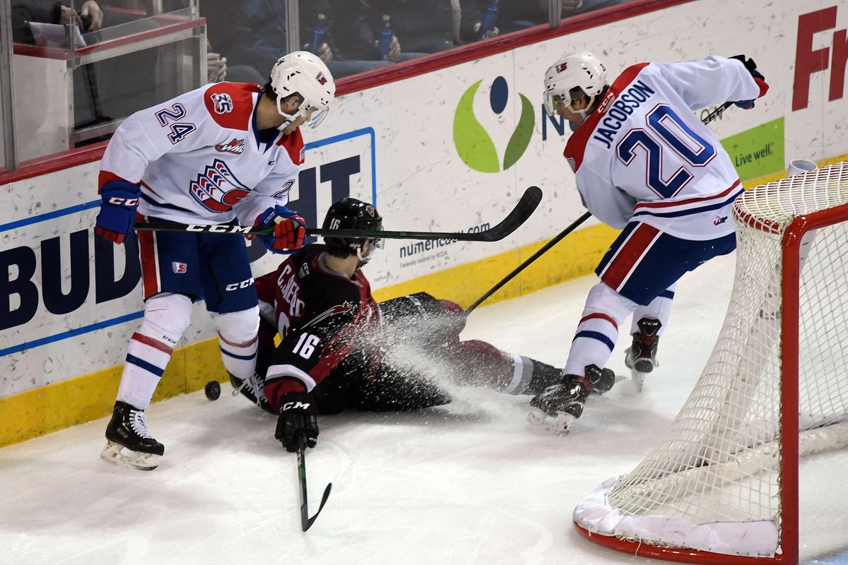 Vancouver Giants forward Cole Shepard (16) falls as Spokane Chiefs forward Ty Smith (24) and  forward Reed Jacobson (20) dig for the puck along the boards during the first period of a WHL hockey game, Fri., Jan. 10, 2020, in the Spokane Arena. (Colin Mulvany / The Spokesman-Review)