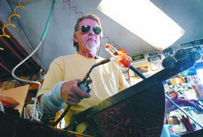 Artist Steve Adams shapes molten glass into a paperweight with a red heart in his Vinegar Flats studio. Below are finished 