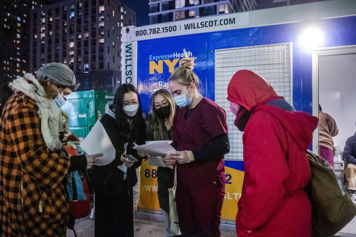 People check their rapid COVID-19 test results outside of a testing site on the Lower East Side of Manhattan, Tuesday, Dec. 21, 2021, in New York.  (Brittainy Newman)