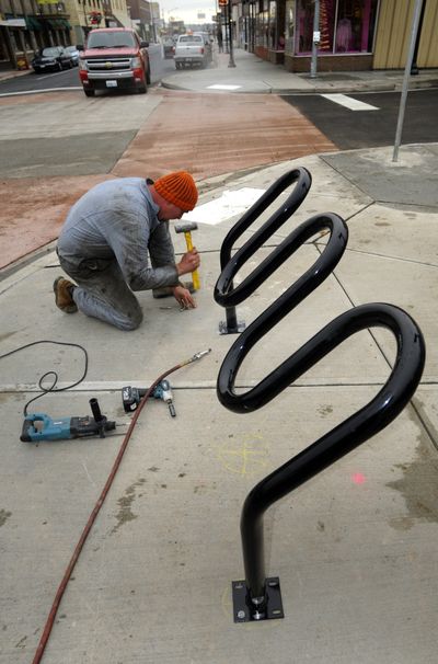 Chris Helberg installs a bike rack Tuesday at Queen Avenue and Market Street. Workers are putting finishing touches on a project to rebuild Market from Garland to Francis avenues. (Colin Mulvany)