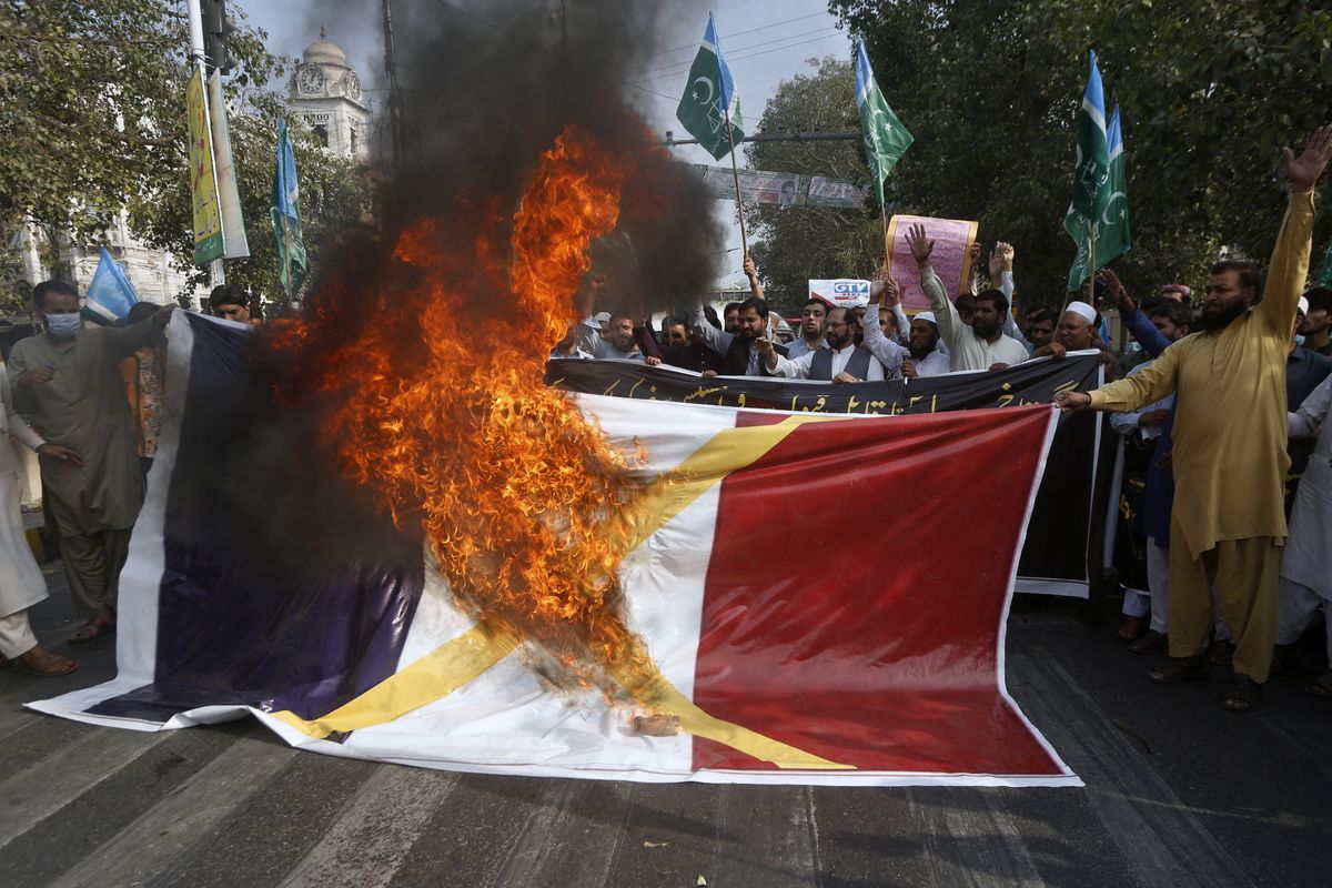 Supporters of religious group burn a representation of a French flag during a rally against French President Emmanuel Macron and republishing of caricatures of the Prophet Muhammad they deem blasphemous, in Lahore, Pakistan, Friday, Oct. 30, 2020. Muslims have been calling for both protests and a boycott of French goods in response to France