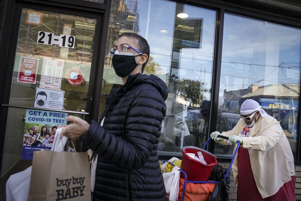 Pedestrians in protective masks pass a storefront on Thursday, Oct. 15, 2020, as restrictions on operations are imposed due to an increase in COVID-19 infections in the Far Rockaway neighborhood of the borough of Queens in New York. After shutdowns swept entire nations during the first surge of the coronavirus earlier this year, some countries and U.S. states are trying more targeted measures as cases rise again around the world. New York’s new round of shutdowns zeroes in on individual neighborhoods, closing schools and businesses in hot spots measuring just a few square miles.  (John Minchillo)