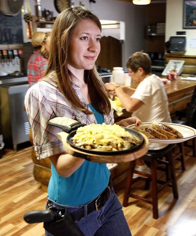 Jessie Spaulding, a waitress at the Shooters Grill in Rifle, Colo., takes food to a table last month. (Associated Press)