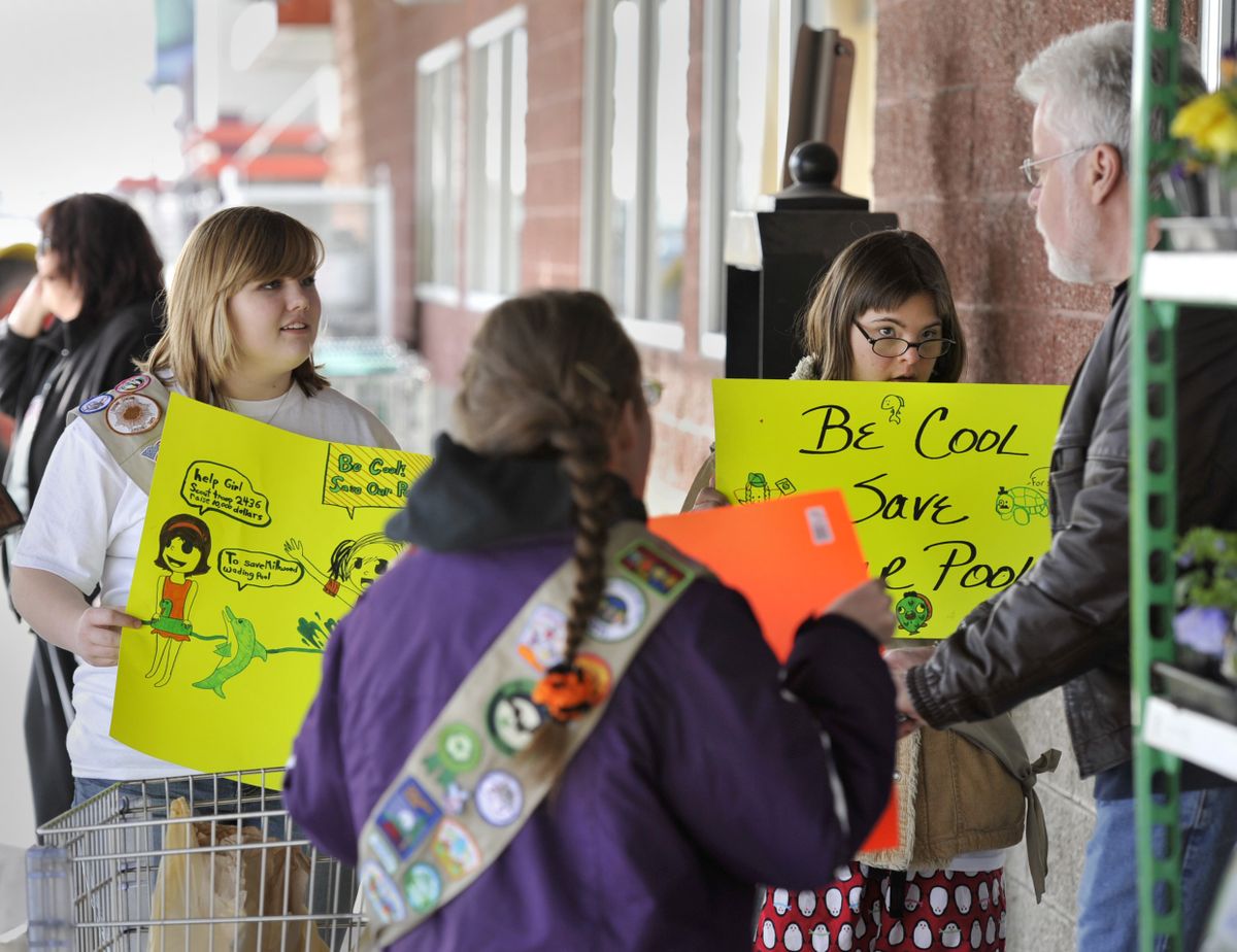 Girls Scout Cadette Troop 2436 members, from left, Emma Porter, Victoria Harding and Mariah Bechtel ask Argonne Village Yoke’s shopper, Ron Irwin, far right, to buy cookies or donate money to help save Millwood’s wading pool. Irwin bought two boxes of cookies. (Dan Pelle)